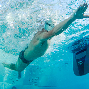 Underwater view of a man swimming in a swim spa.