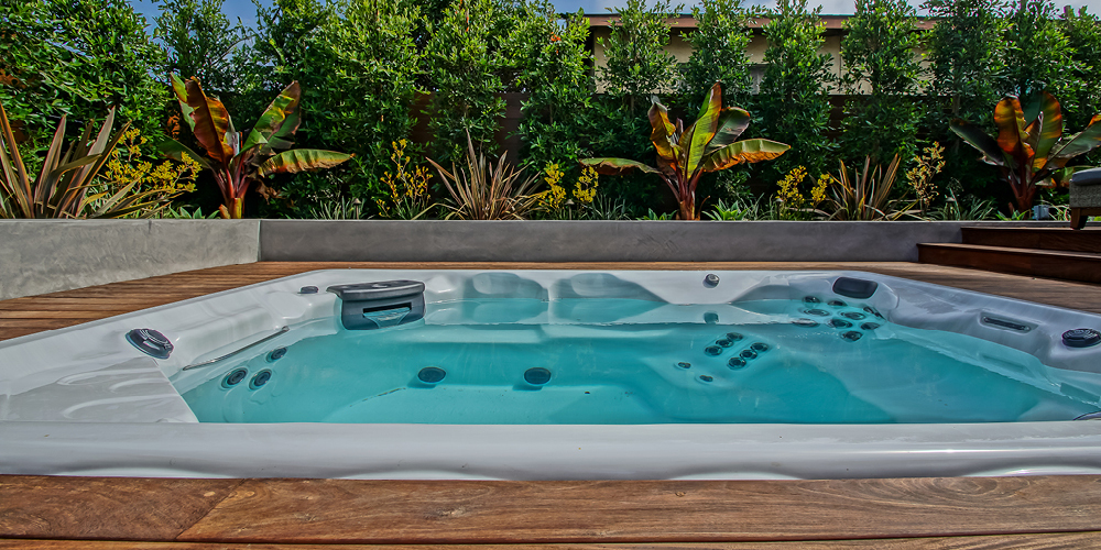 Close up view of a swim spa on a deck.