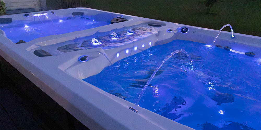 View of a swim spa at night with water features and leds on.